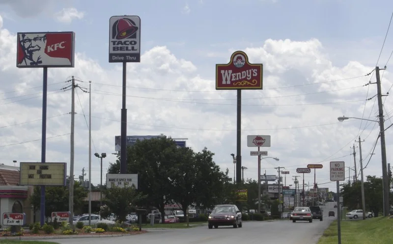 Zdjęcie ulicy z widocznymi tablicami fast foodów: między innymi KFC, Wendy’s i Taco Bell. Zrobione w Bowling Green, KY